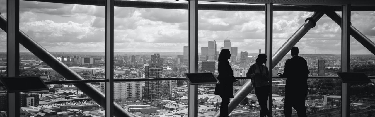 Black and white of 3 people in a building overlooking the city.