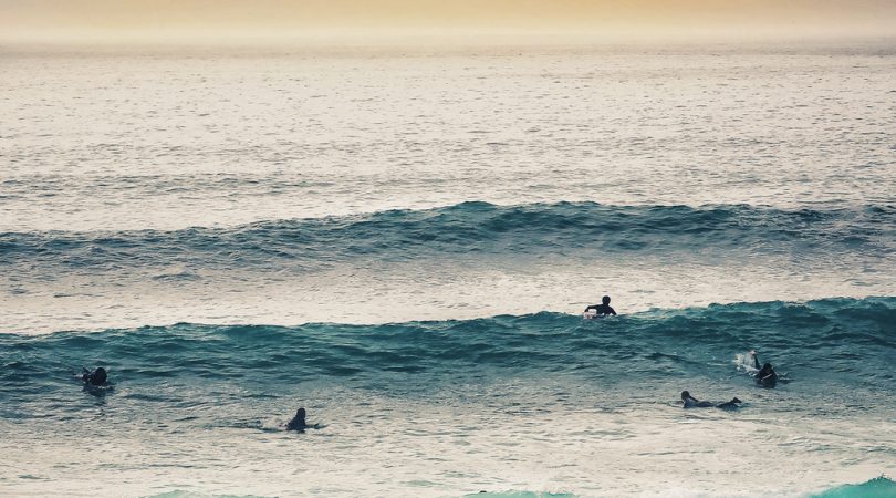 Swimmers and surfers in blue ocean with big waves